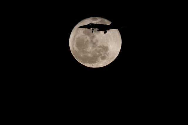 A fighter aircraft McDonnell Douglas F/A-18 Hornet of the Spanish Air Force crosses the full moon known as the "Pink Moon", over the island of Gran Canaria in Spain on April 24, 2024.