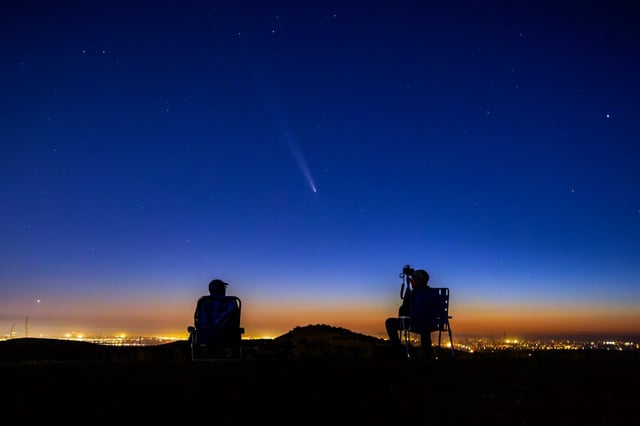 Comet Tsuchinshan-ATLAS makes an appearance in the western night sky as amateur photographers Nolan Letellier, left, and Link Jackson observe on a ridge near the Dry Creek Trailhead in Boise, Idaho, Oct. 14, 2024 (Kyle Green/AP)