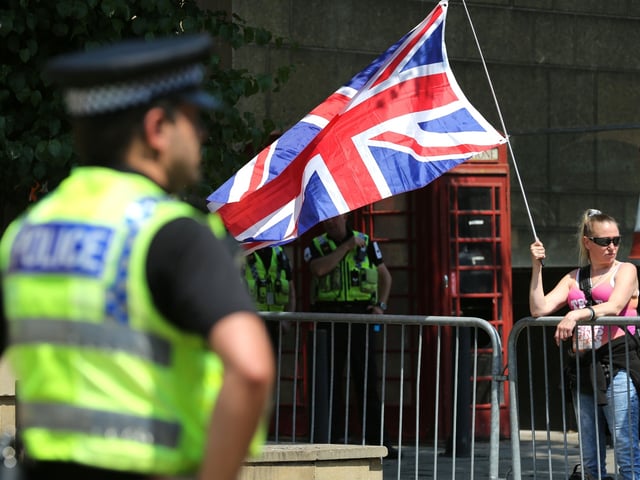 LEEDS, ENGLAND - JUNE 10: A protester against further immigration waves a union flag towards the counter demonstration surrounded by barriers and police officers on June 10, 2023 in Leeds, England. Protesters gathered to say "Enough is Enough". They argue the UK has received enough immigration over the last number of years and it should be stopped immediately. Counter protesters argue that refugees and immigrants need our help and should be welcomed. (Photo by Martin Pope/Getty Images)