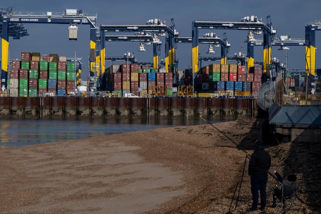A man, while fishing, points towards shipping containers at the Port of Felixstowe in Felixstowe, Britain, February 17, 2025. REUTERS/Chris J. Ratcliffe/File Photo