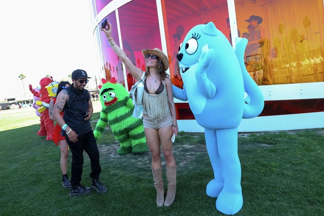 Brobee (in the green costume) and Toodee (in the blue costume) from the children&#39;s musical TV show &#34;Yo Gabba Gabba!&#34; pose with festivalgoers in front of the Spectra Tower during the 2025 Coachella Valley Music and Arts Festival at Empire Polo Club on April 11, 2025 in Indio, Calif.
