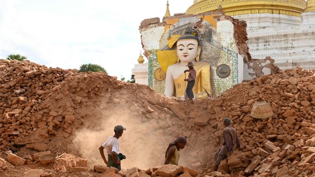 People clear debris of a damaged Buddha statue at Lawkatharaphu pagoda in Inwa on the outskirts of Mandalay on April 12, 2025.
