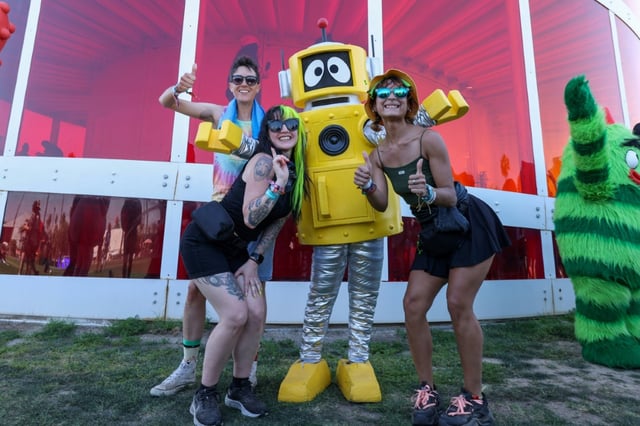 Plex from children's musical television show "Yo Gabba Gabba!" poses with festivalgoers in front of the Spectra Tower during Coachella 2025