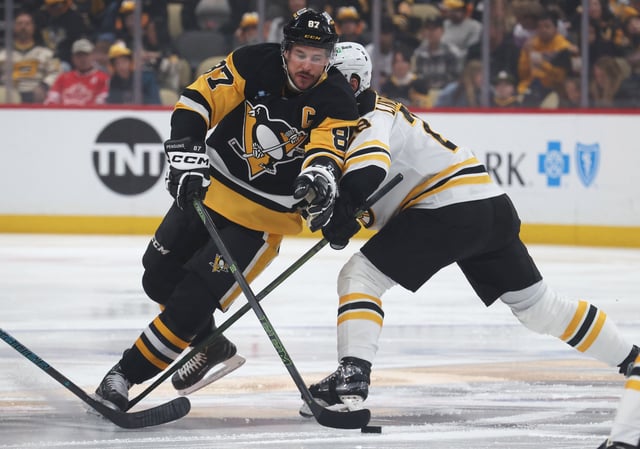 Apr 13, 2025; Pittsburgh, Pennsylvania, USA;  Pittsburgh Penguins center Sidney Crosby (87) moves the puck against Boston Bruins center Elias Lindholm (28) during the first period at PPG Paints Arena. Mandatory Credit: Charles LeClaire-Imagn Images