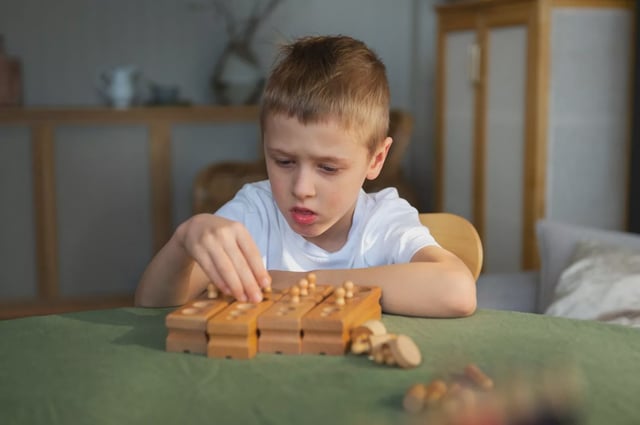 Young autistic boy playing with toys at home