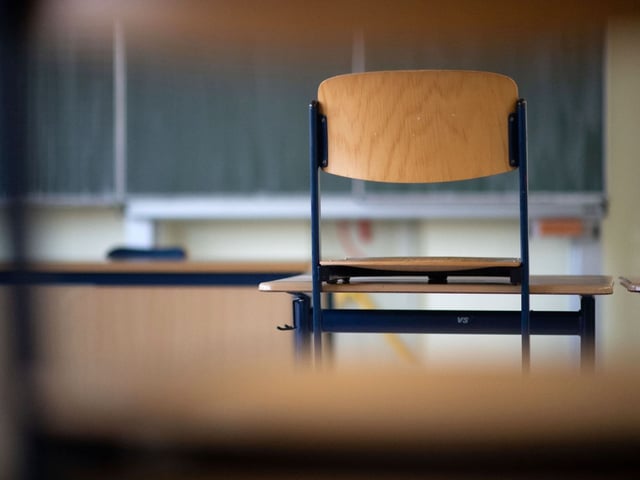 Ein Stuhl steht in einem Klassenzimmer auf dem Tisch.