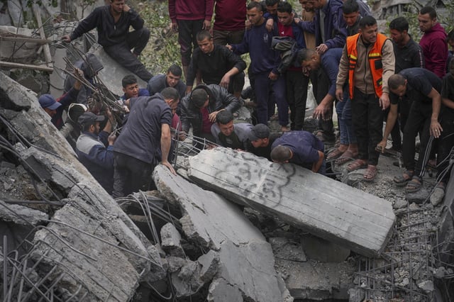 Volunteers and emergency workers try to move a concrete pillar as they search for bodies and survivors from the rubble of the Manoun family's house after it was targeted by an Israeli army strike in Jabalia al-Balad, Gaza City, Sunday, April 13, 2025. (AP Photo/Jehad Alshrafi)