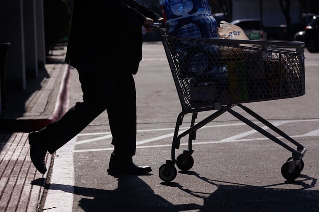 A customer pushes a shopping cart outside a Kroger grocery store in Dallas on Feb. 21, 2024.