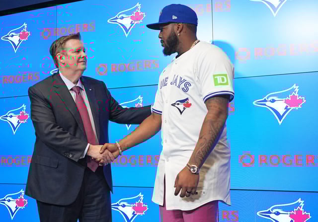 Apr 14, 2025; Toronto, Ontario, Canada; Toronto Blue Jays Vladimir Guerrero Jr. shakes hands with Chairman of the board of directors of Rogers Communications Edward S. Rogers III during the press conference at Rogers Centre. Mandatory Credit: Nick Turchiaro-Imagn Images