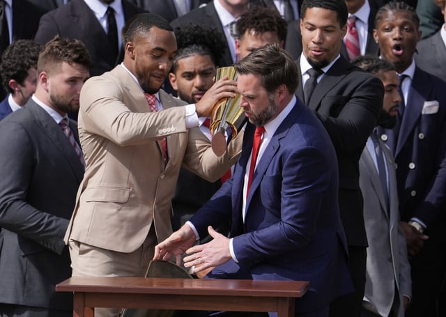Ohio State University football player TreVeyon Henderson, left, holds the top of the team's championship trophy as Vice President JD Vance reaches to catch it's base after it fell off, as President Donald Trump welcomes the 2025 College Football National Champions during an event on the South Lawn of the White House, Monday, April 14, 2025, in Washington. (AP Photo/Manuel Balce Ceneta)