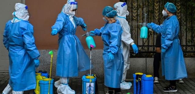 Des travailleurs se désinfectent entre eux dans un quartier résidentiel sous confinement pour cause de Covid-19 à Shanghai, en Chine, le 4 juin 2022