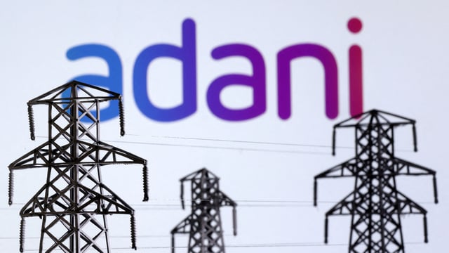 Electric power transmission pylon miniatures and Adani Green Energy logo are seen in this illustration taken, December 9, 2022.