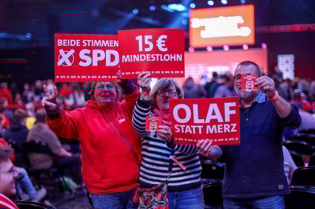 Auf einer Wahlkampfveranstaltung halten SPD-Mitglieder Schilder mit Mindestlohnforderungen hoch. Das könnte der Wirtschaft schaden.