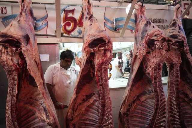 A worker cuts meat at a butcher shop in Buenos Aires, Argentina, Monday, April 14, 2025. (AP Photo/Natacha Pisarenko)
