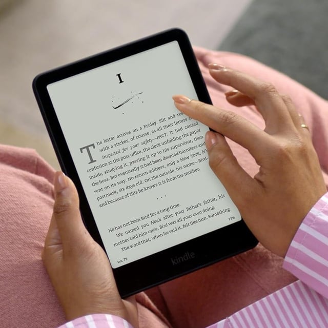 a person holds an amazon kindle paperwhite while the device shows text of chapter 1
