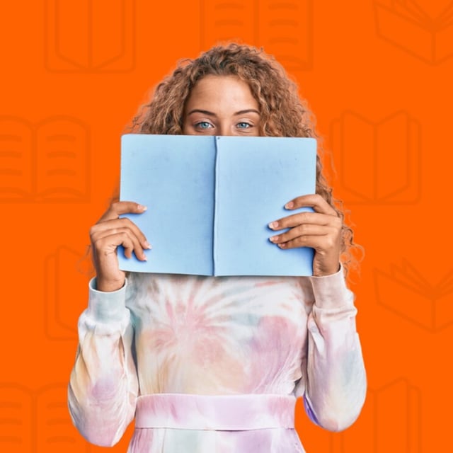 A person holding a book in front of an orange background.