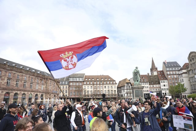 People wave a Serbian flag before Serbian university students riding bicycles from Novi Sad, Serbia, and who say their fight for justice and the rule of law, arrive the heart of the European Union to seek support, Tuesday, April 15, 2025 in Strasbourg, eastern France. (AP Photo/Antonin Utz)