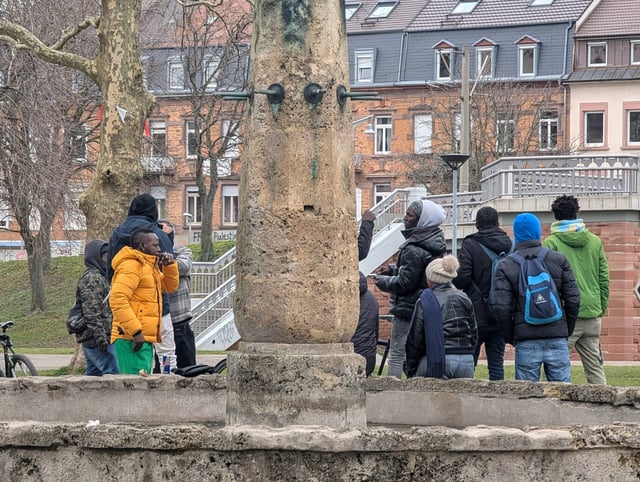 Keine Abschiebung in Sicht? Afrikanische Migranten in einem Park Eine Gruppe afrikanischer Migranten versammelt sich am 23. Februar 2025 in einem Park in Freiburg im Breisgau, Baden-Württemberg, Deutschland. Einige stehen, während andere in der Nähe eines Wasserbrunnens oder auf Bänken sitzen. Die Umgebung besteht aus blattlosen Bäumen, Wohngebäuden im europäischen Stil und einer Mischung aus städtischen und grünen Flächen. Freiburg im Breisgau, Deutschland. Afrikanische Migranten in einem Park in Freiburg im Breisgau: Tausende Ausreisepflichtige erhielten Aufenthaltstitel. Foto: IMAGO / NurPhoto