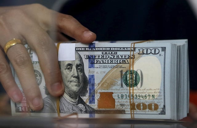 An employee of a money changer holds a stack of U.S.  Dollar notes before giving it to a customer in Jakarta, October 8, 2015. REUTERS/Beawiharta/File Photo