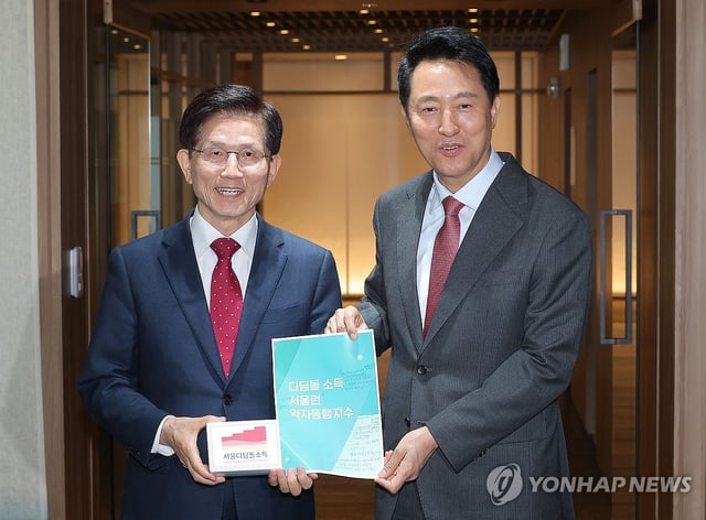 Former Labor Minister Kim Moon-soo (L) and Seoul Mayor Oh Se-hoon pose for a photo after their meeting at Seoul City Hall on April 16, 2025. (Yonhap) 