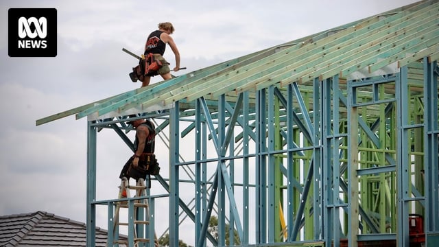 Tradies work on the roof frame of a new home under construction.
