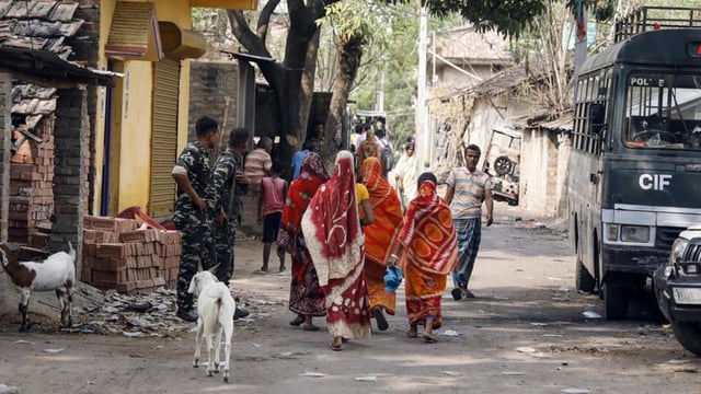 Paramilitary personnel stand guard as women in violence-affected in Murshidabad step out on Tuesday. (ANI Photo)