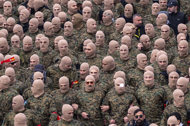 Hezbollah fighters surround a trailer carrying the bodies of Hezbollah's former leader Hassan Nasrallah and his cousin and successor Hashem Safieddine, during a funeral procession at the Sports City Stadium in Beirut, Lebanon on February 23.