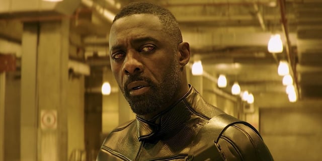Idris Elba as Brixton in yellow lights looks at something off-screen in Fast & Furious Presents Hobbs & Shaw