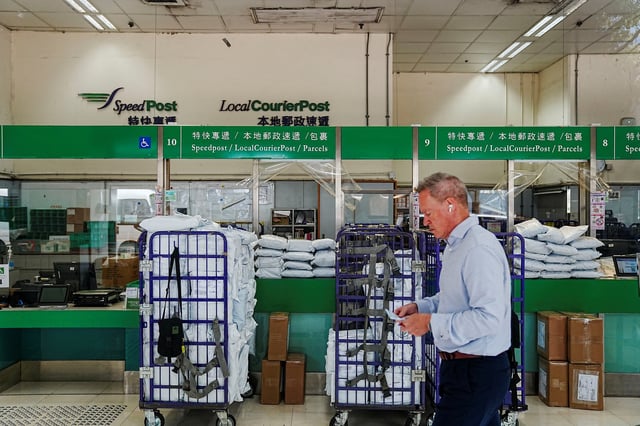 A customer walks past the General Post Office in Hong Kong, China April 9, 2025. Picture taken through glass. 