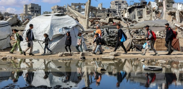 Des palestiniens marchent près des décombres d'un bâtiment effondré dans le quartier de Nasr, à l'ouest de la ville de Gaza, le 15 avril 2025