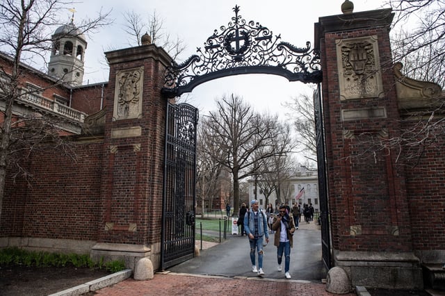 People walk through a gate as they exit Harvard Yard on the campus of Harvard University campus in Cambridge, Massachussetts, on April 15, 2025.
