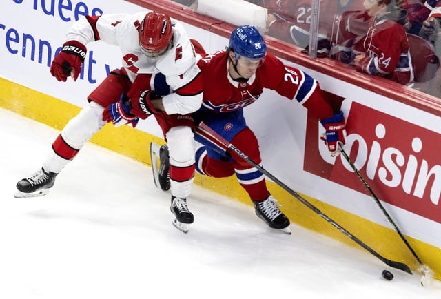 Montreal Canadiens' Juraj Slafkovsky (20) holds off Carolina Hurricanes' Shayne Gostisbehere (4) during second period NHL hockey action in Montreal on Wednesday, April 16, 2025.