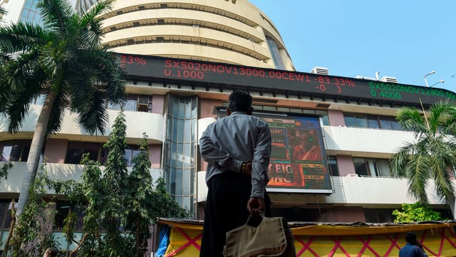 A pedestrian watches a digital screen on the facade of the Bombay Stock Exchange (BSE) in Mumbai.