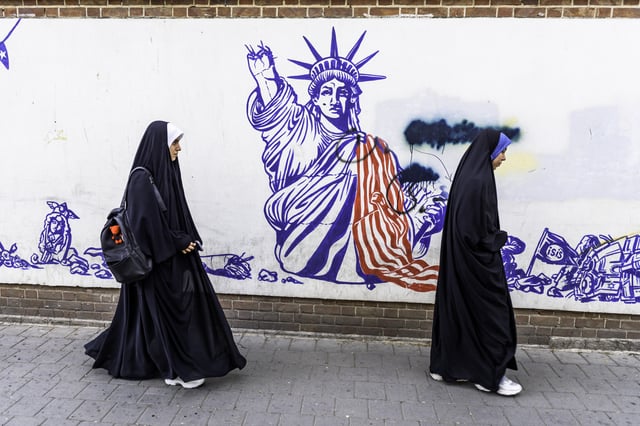 Iranian women walk by the anti-US murals on the walls of the former US embassy in downtown Tehran, Iran on April 11, 2025.