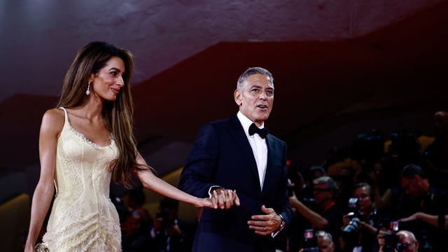 George Clooney and Amal Clooney walk on the red carpet during arrivals for the movie 'Wolfs'.