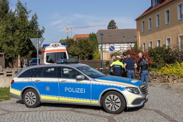 Einsatzkräfte von Polizei und Rettungsdienst stehen am Einsatzort in Zeithain