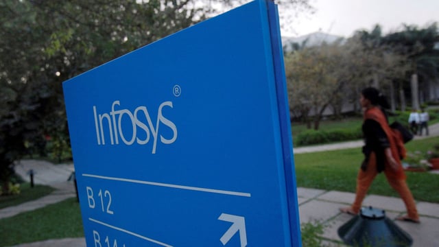 FILE PHOTO: An employees walks past a signage board in the Infosys campus at the Electronics City IT district in Bangalore, February 28, 2012. 