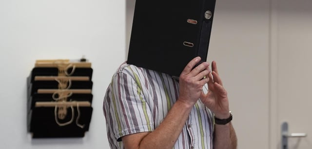 Der Angeklagte verbarg zum Prozessbeginn sein Gesicht mit einem Aktenordner
