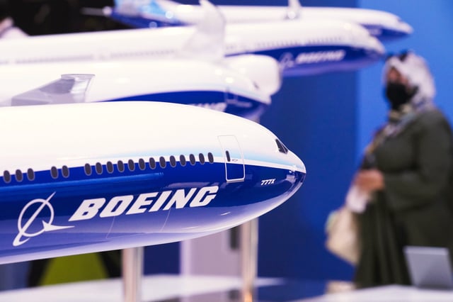 A woman walks by models of Boeing Co. aircraft, including the manufacturer&#39;s Boeing 777X, at the Dubai Air Show in Dubai, United Arab Emirates, Wednesday, Nov. 17, 2021. (