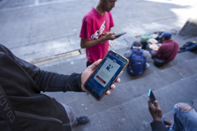 A migrant shows the U.S. Customs and Border Protection (CBP) One app on his cell phone, which he said he used to apply for asylum in the U.S. and is waiting on an answer, at a migrant tent camp outside La Soledad church in Mexico City, Jan. 20, 2025