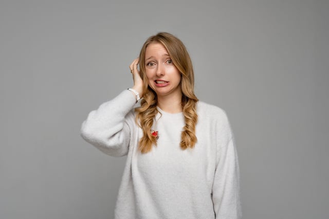 Yikes, oops. Portrait of embarrassed young blonde woman holding hand on head and grimacing with awkward expression, being guilty and hoping that nobody will know about her fault. Emotions concept