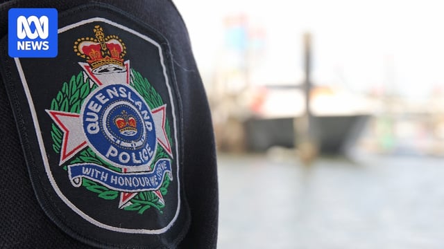 A close-up of a police badge, with a boat on the ocean in the background.