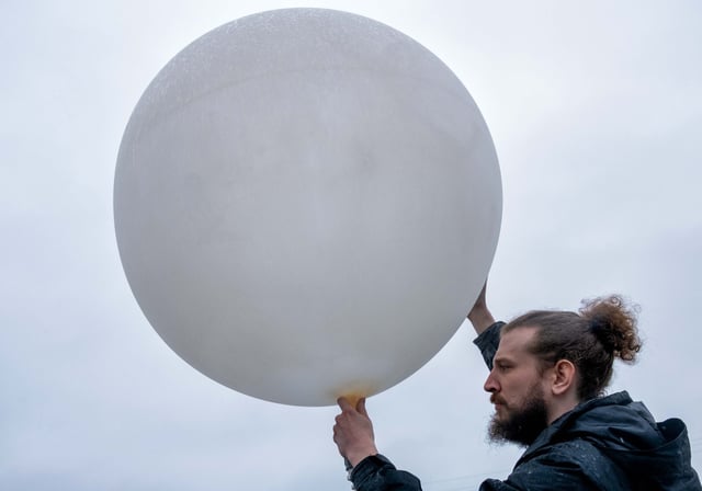 A member of a weather team prepares a weather balloon for release during a NOAA media day to learn about a field campaign to study tornadoes, in Memphis, Tennessee on February 8, 2023.