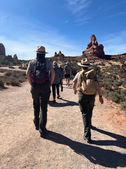 Park rangers walk behind visitors at Arches National Park in Utah.