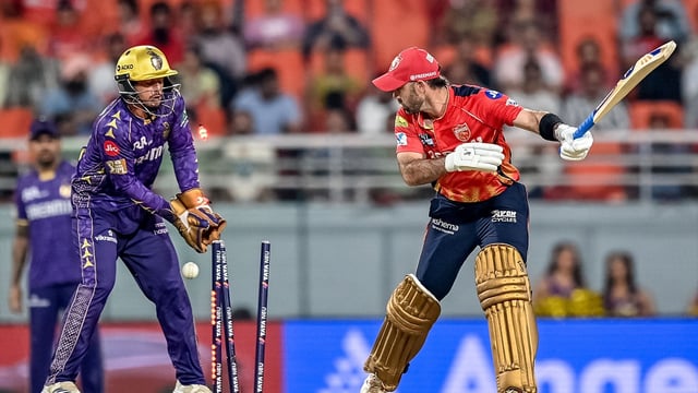 Punjab Kings' Glenn Maxwell (R) is clean bowled by Kolkata Knight Riders' Varun Chakravarthy
