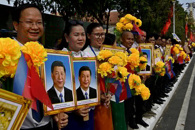Cambodians hold portraits of China&#39;s President Xi Jinping and Cambodia&#39;s King Norodom Sihamoni during a welcome ceremony in front of the Royal Palace in Phnom Penh on April 17, 2025.