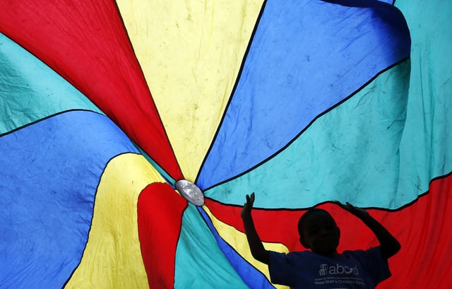 A child from the Hyde Park Head Start program is silhouetted as he plays underneath a parachute during a celebration of 50 years of the Head Start program on the Boston Common in Boston, Massachusetts June 9, 2015.