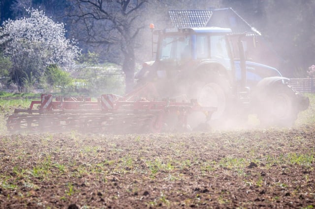 Traktor fährt über vor Trockenheit staubenden Acker