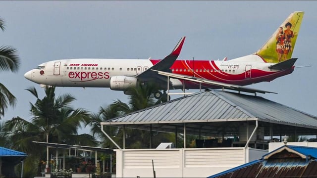 An Air India Express flight is seen behind a residential area during its landing at the airport in Thiruvananthapuram. (PTI FILE PHOTO)