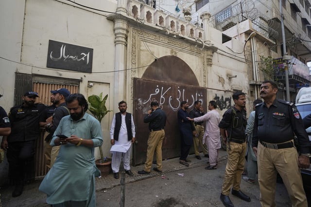 Police officers stand guard at outside the Pakistan's minority Ahmadi community's place of worship, where supporters of Tehreek-e-Labbaik Pakistan or TLP party hold a demonstration against the Ahmadi, in Karachi, Pakistan, Friday, April 18, 2025. (AP P hoto/Fareed Khan)